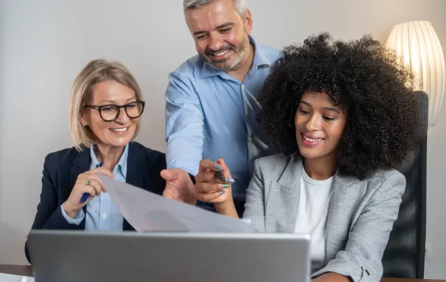 Three people sitting at a laptop